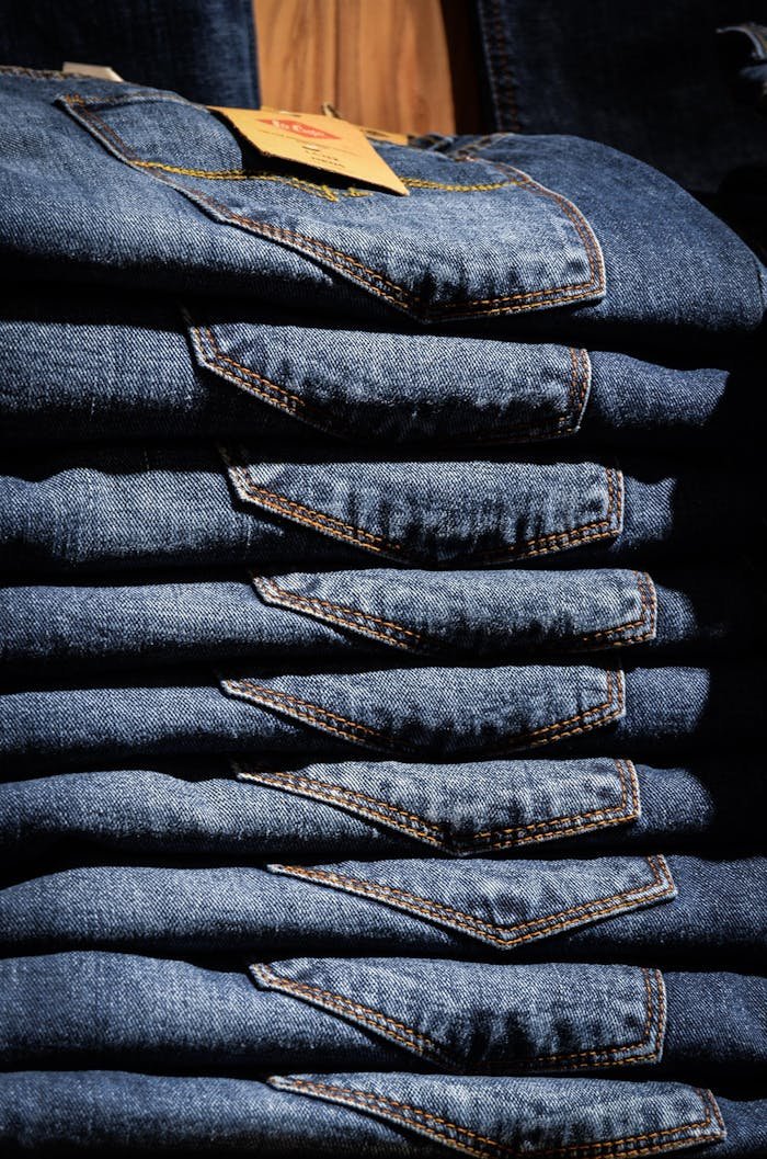 Neatly stacked blue jeans with visible price tag in retail setting.