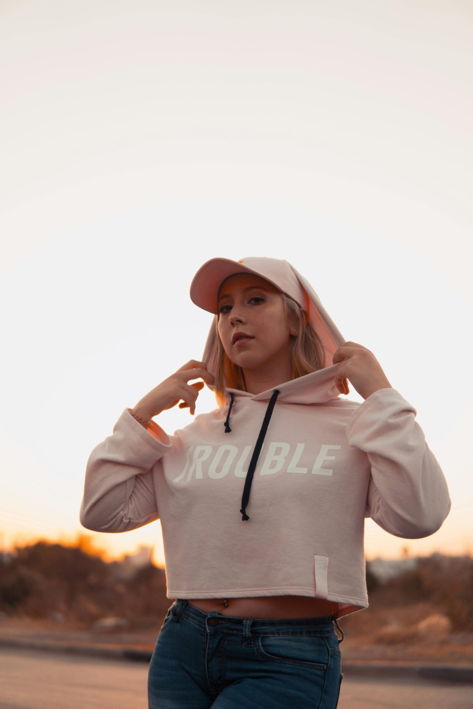 Young woman in a pink hoodie posing outdoors during a beautiful sunset in Rabat, Morocco.